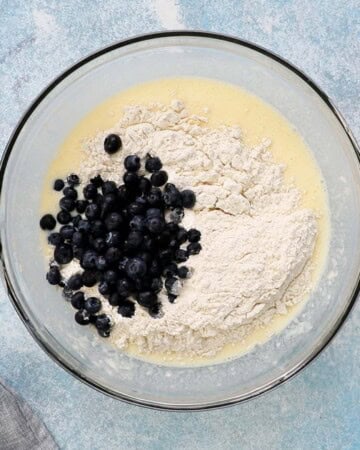 blueberries and white flour in a large glass bowl.
