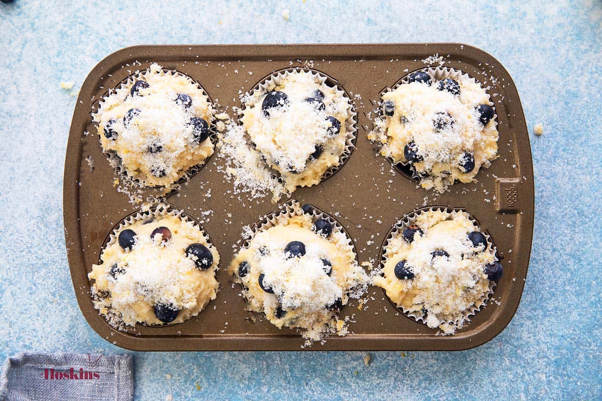 6 cup muffin pan filled with blueberry muffin batter.