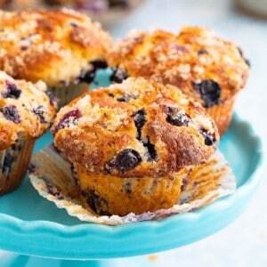 4 blueberry muffins on a blue cake stand.