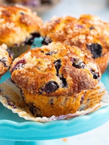 4 blueberry muffins on a blue cake stand.