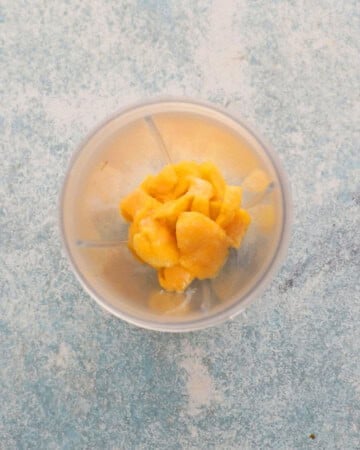 cut mango pieces in a transparent blender.