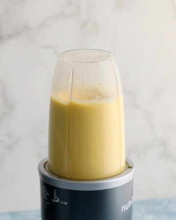 yellow colored drink being blended in a blender.