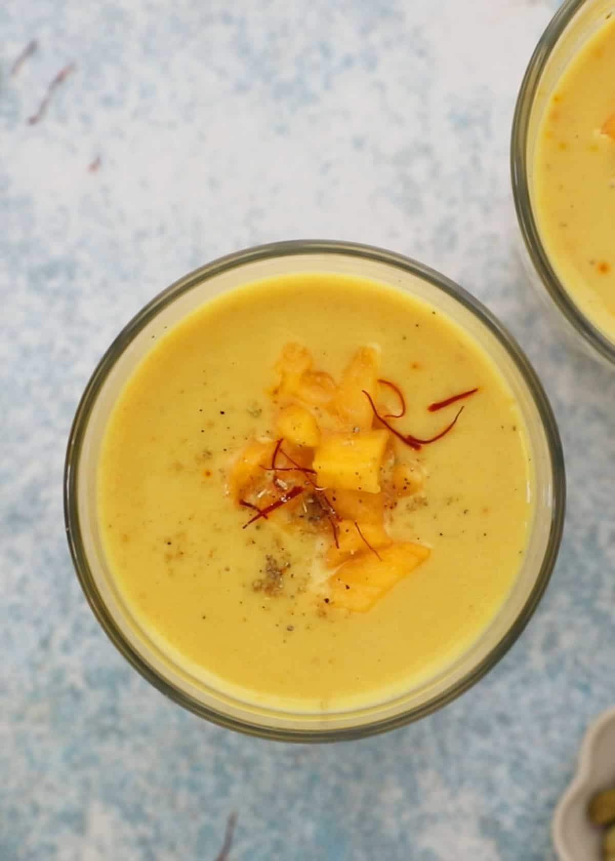 yellow colored mango milk in two drinking glasses.