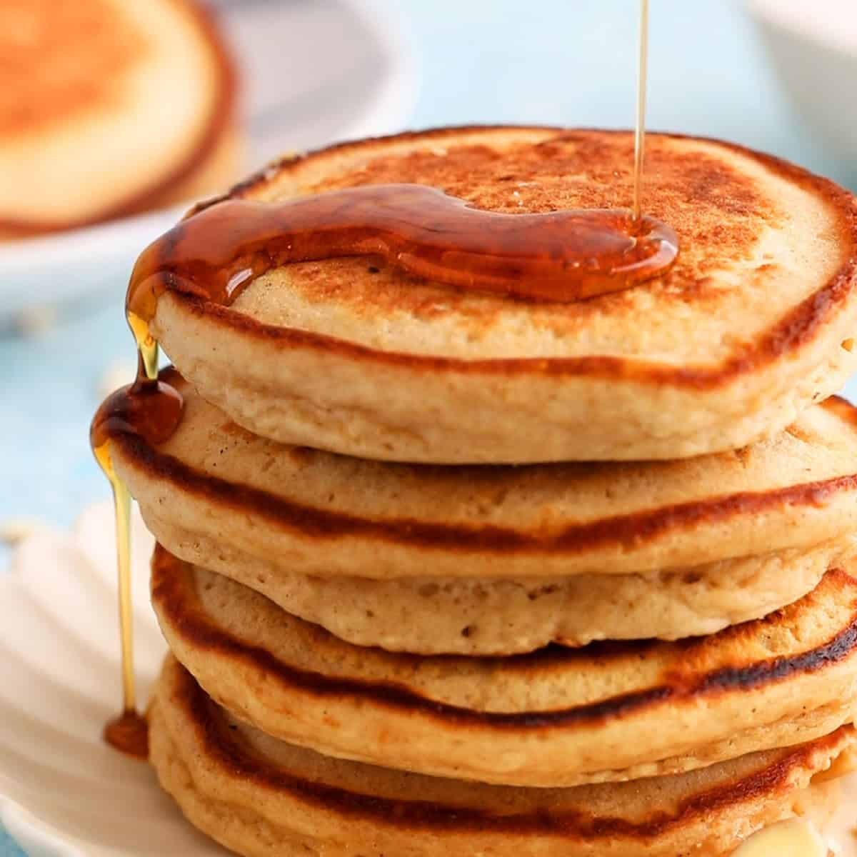 5 pancakes topped with maple syrup on a white plate.