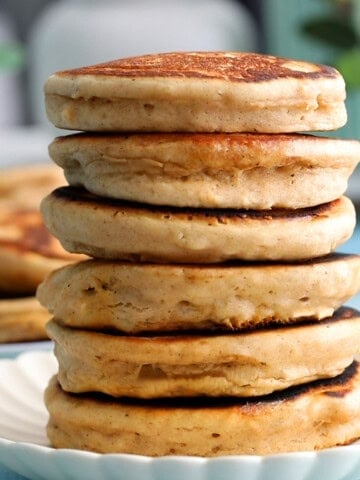 a tall stalk of almond butter pancakes in a white plate.
