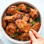 a hand holding one brown chicken wing.