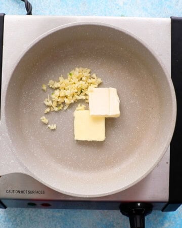 two slices of white butter and chopped garlic in a small white skillet.