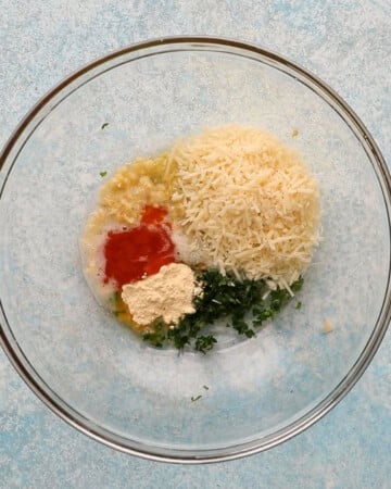 grated white parmesan cheese and spices in a large glass bowl.
