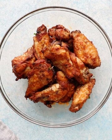 cooked brown chicken wings in a large glass bowl.