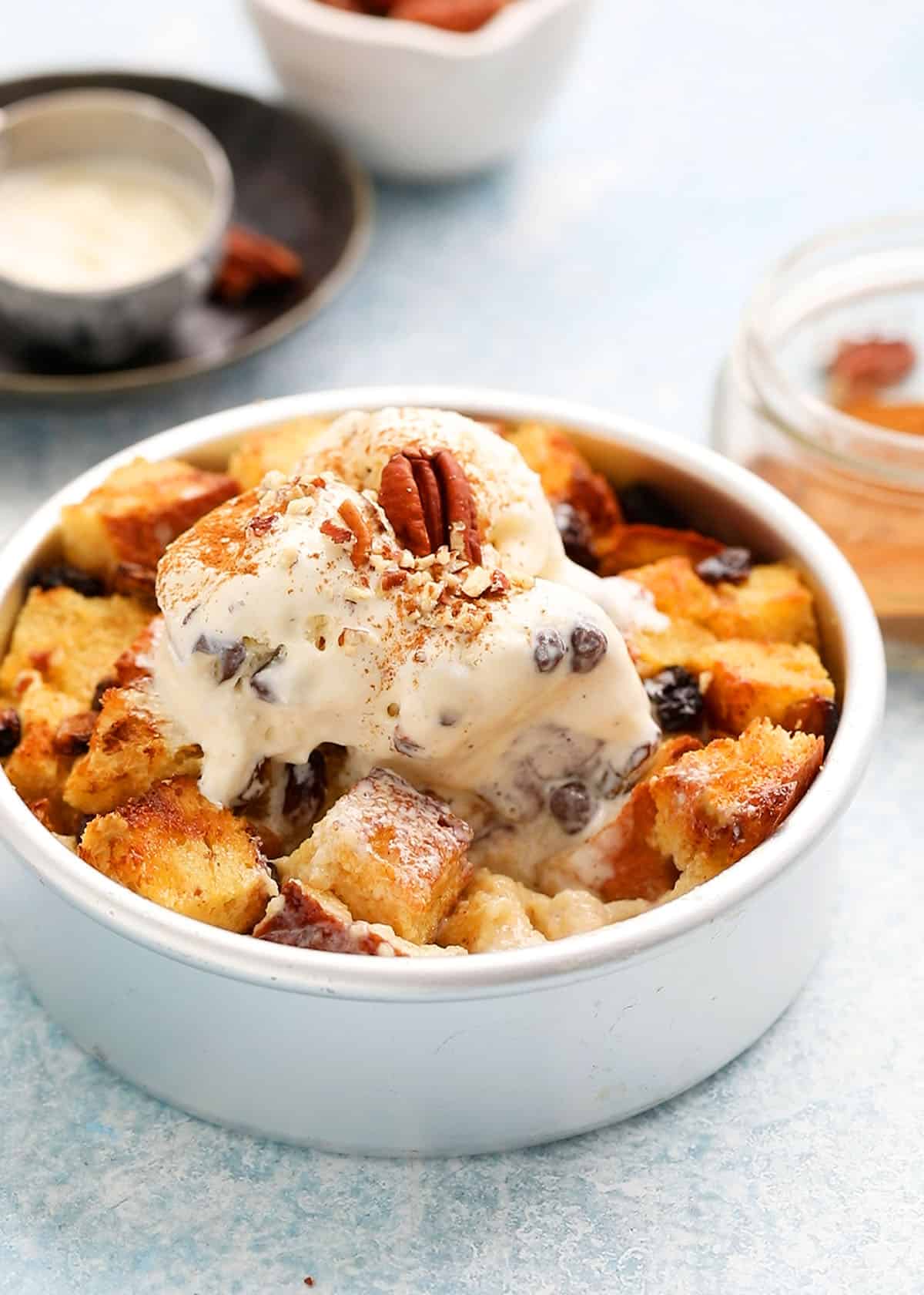 round metal cake pan with bread pudding topped with vanilla ice cream.