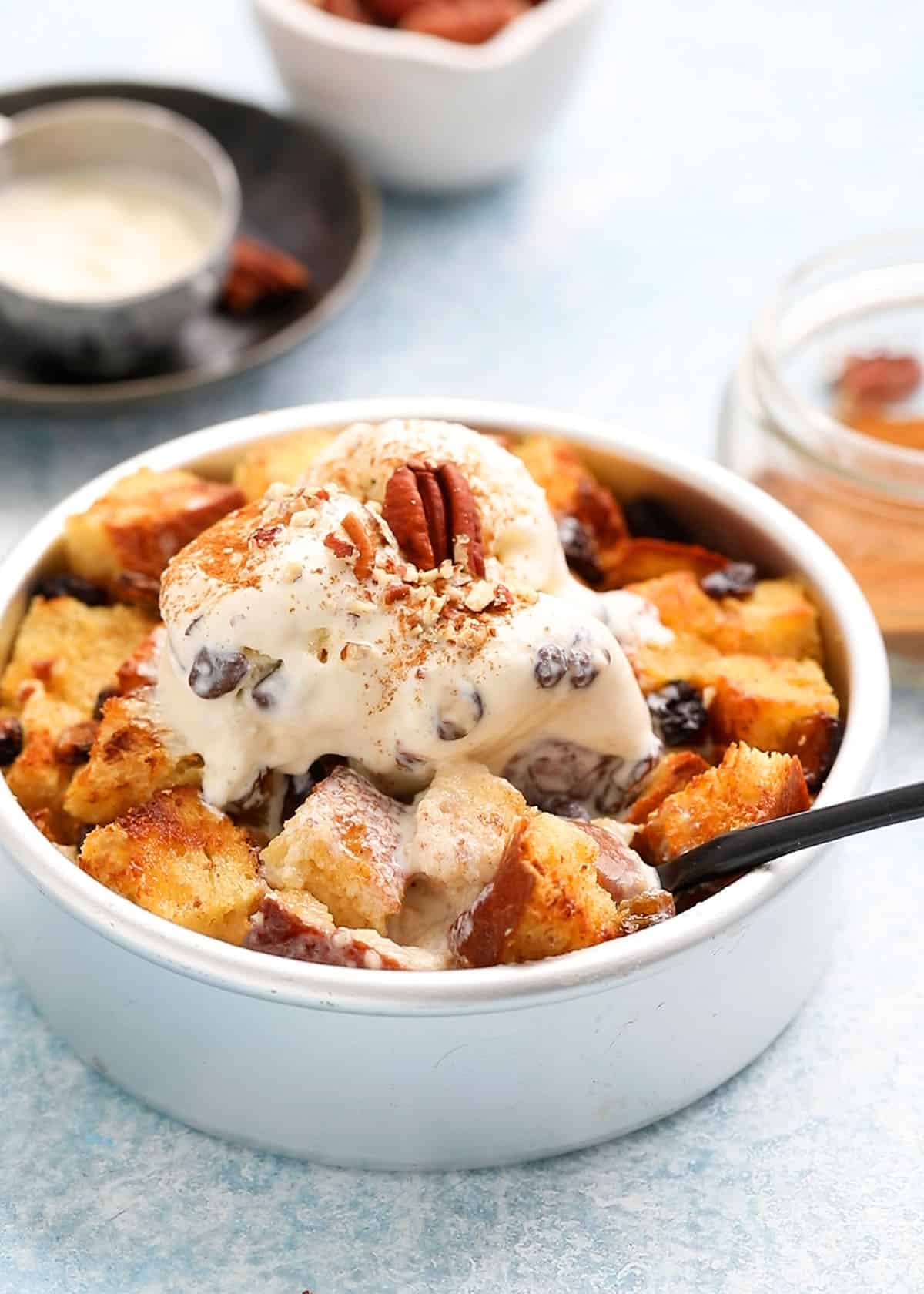 round metal cake pan with bread pudding topped with vanilla ice cream.