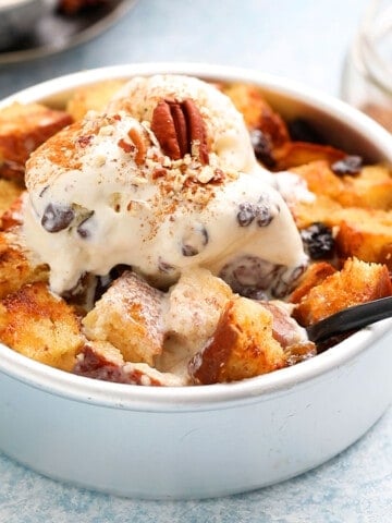 round metal cake pan with bread pudding topped with vanilla ice cream.