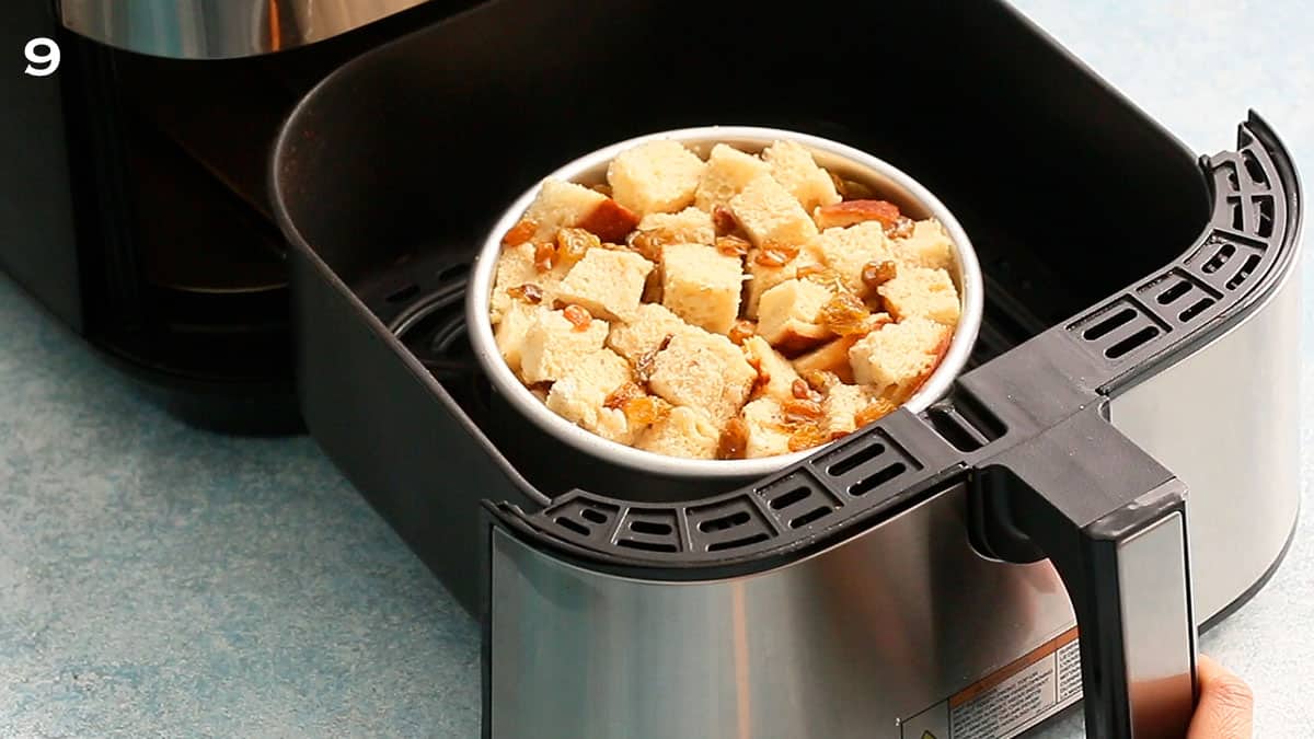 assembled bread pudding in a cake pan placed in a air fryer basket.