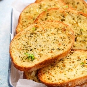 toasted garlic bread slices on a white tray.