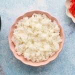 cooked white sushi rice in a pink bowl.
