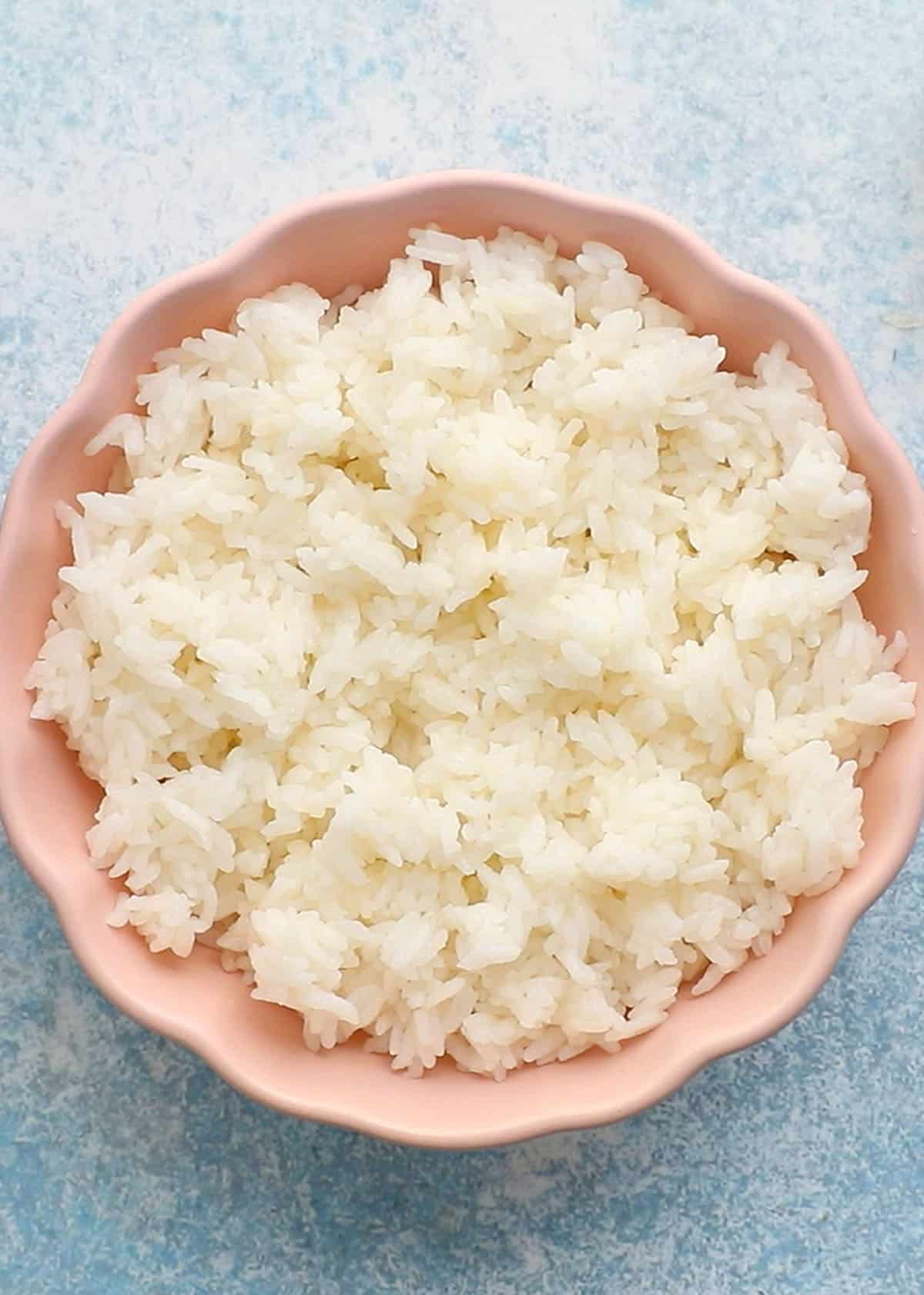 cooked white sushi rice in a pink bowl.