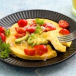 one round omelette topped with tomatoes and avocado.