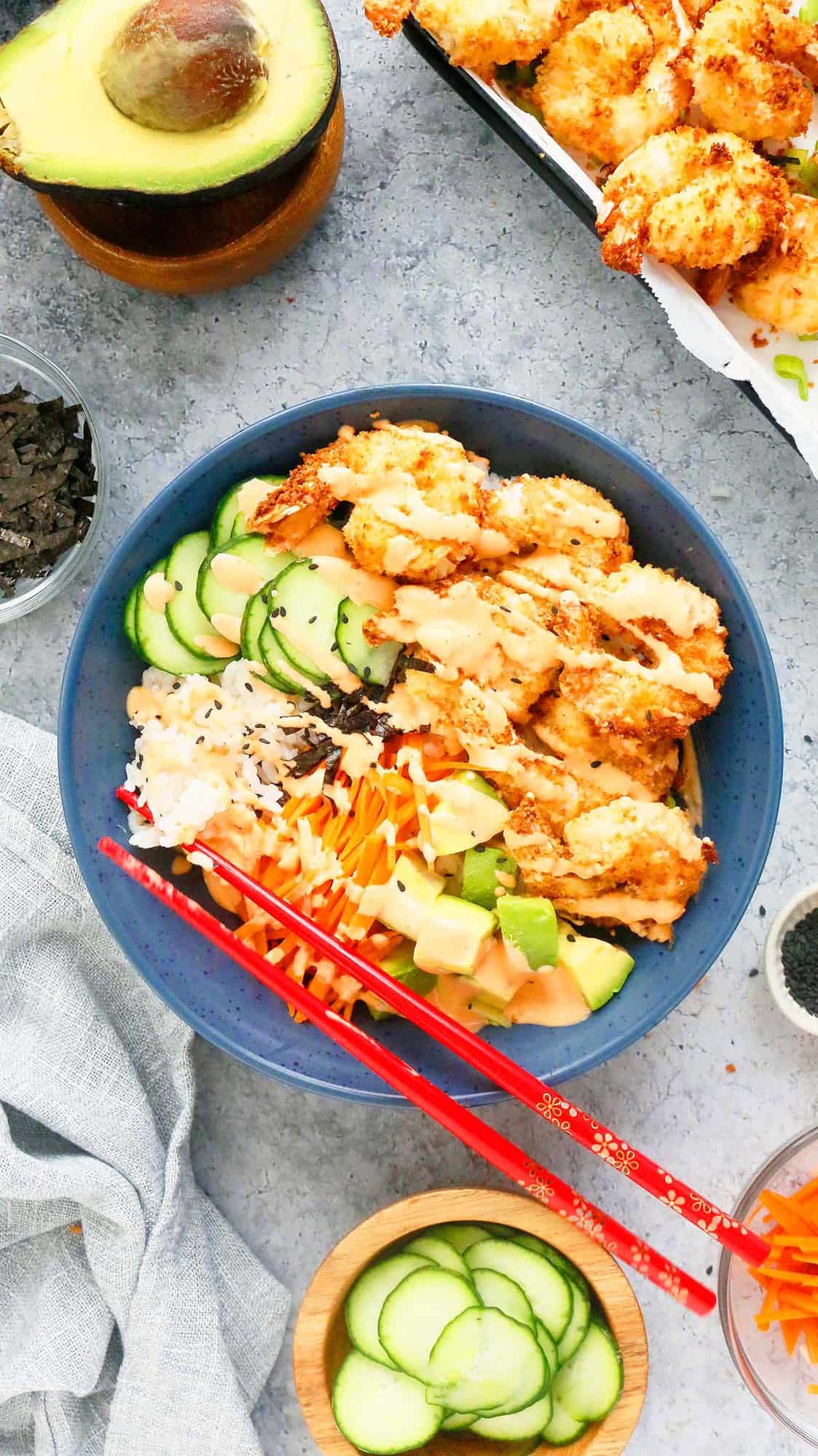 sushi sushi bowl drizzled with spicy sriracha mayo along with red chopsticks