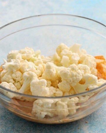 tandoori marinade with cauliflower florets in a glass bowl. 