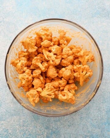 tandoori marinade with cauliflower florets in a glass bowl. 