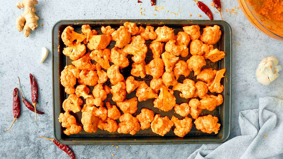 sheet pan with tandoori marinated cauliflower ready to be baked