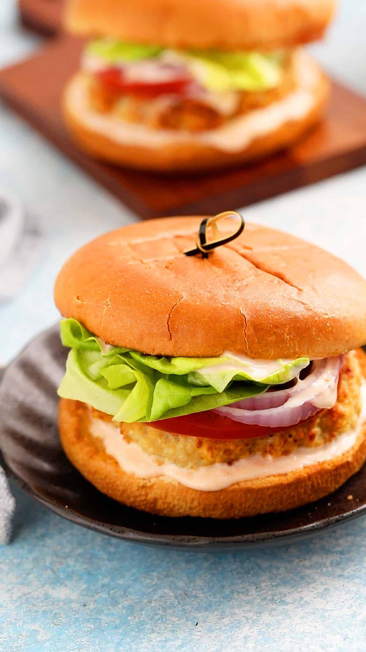 one assembled chicken burger placed on a round black plate.