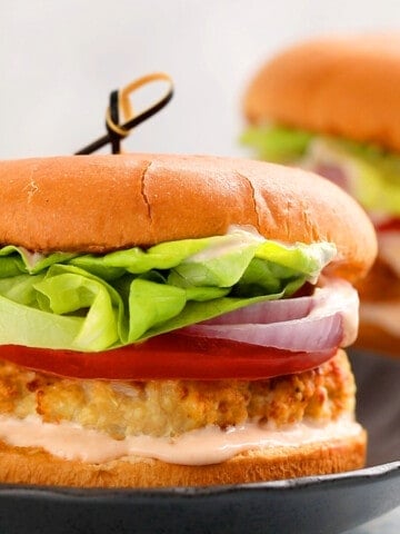 one assembled chicken burger placed on a black round plate.