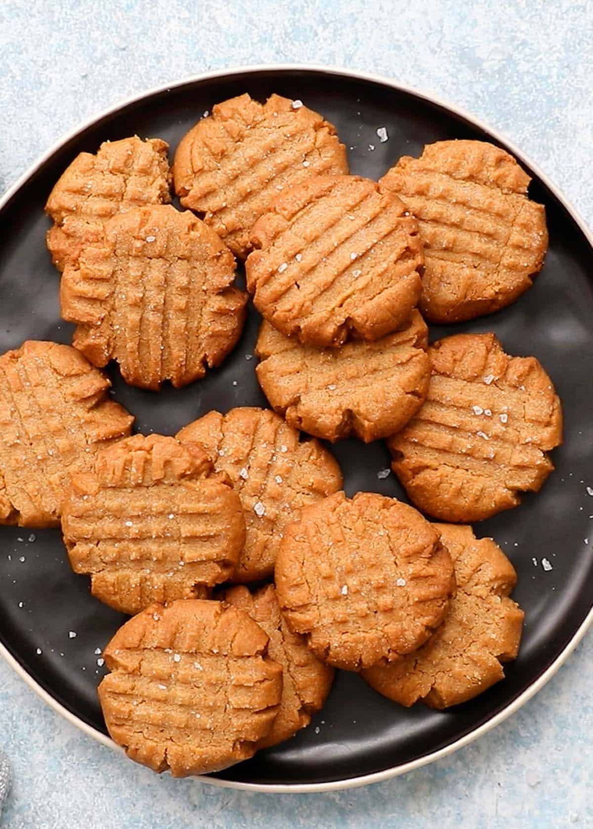 one round black plate filled with almond butter cookies. 