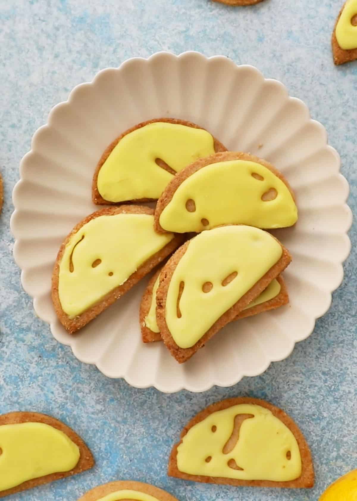 5 almond flour lemon cookies in a white fluted plate.