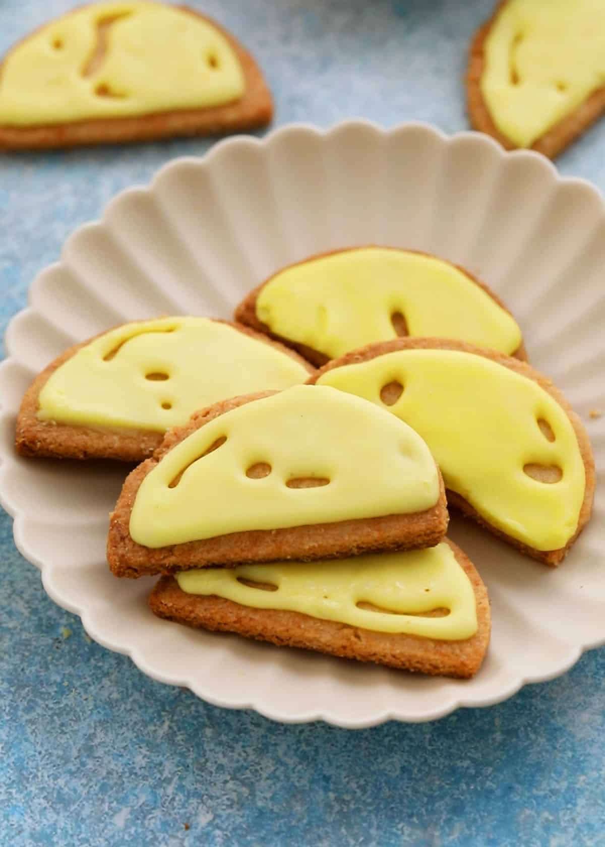 5 almond flour lemon cookies in a white fluted plate.