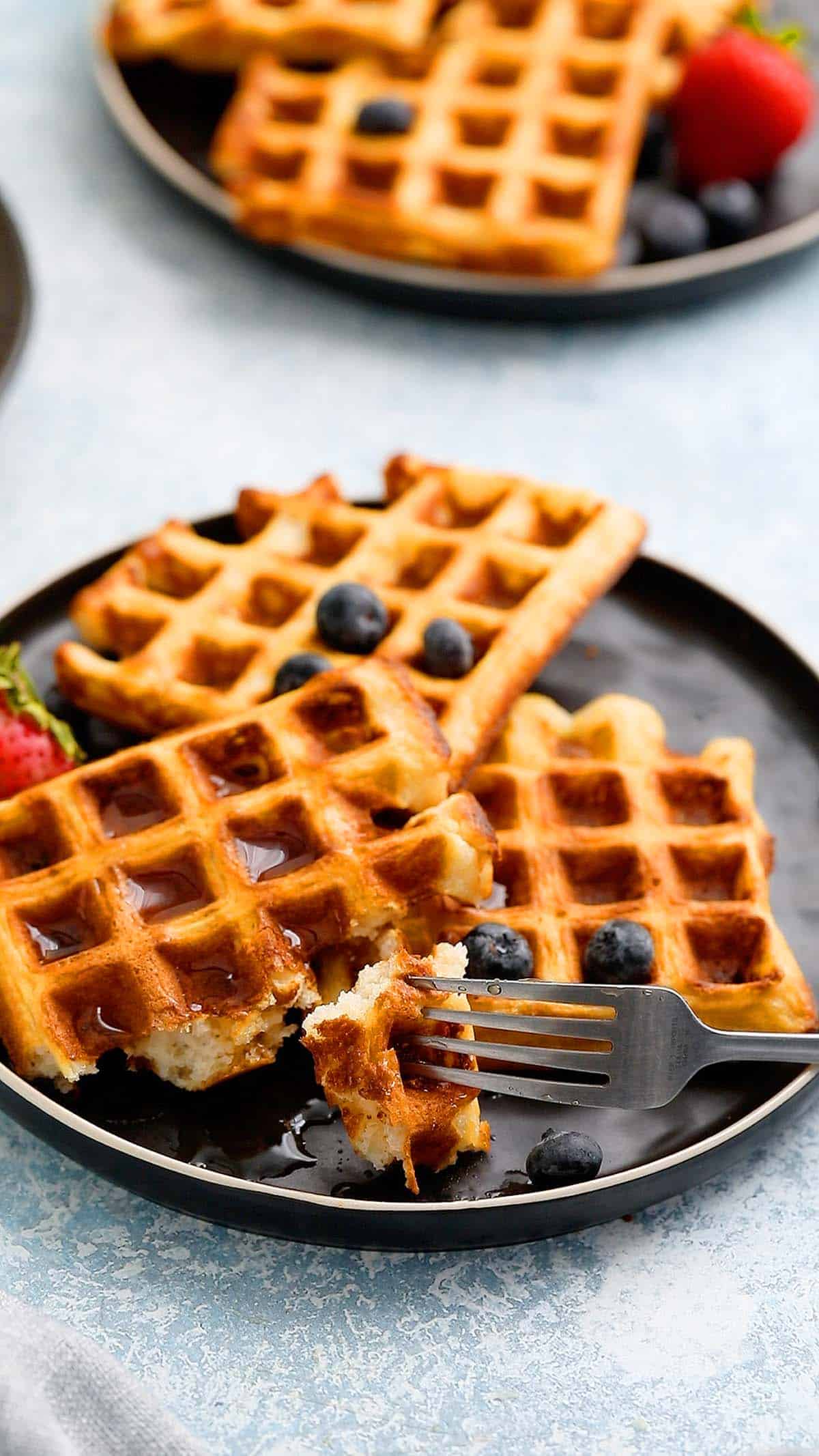 two black plates with 3 waffles on each along with a spoon. 