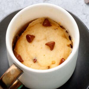 white mug with vanilla cake topped with chocolate chips.