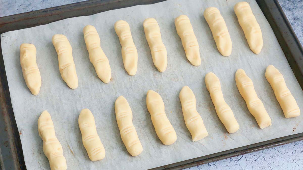 finger shaped cookie dough placed on a parchment lined baking sheet.