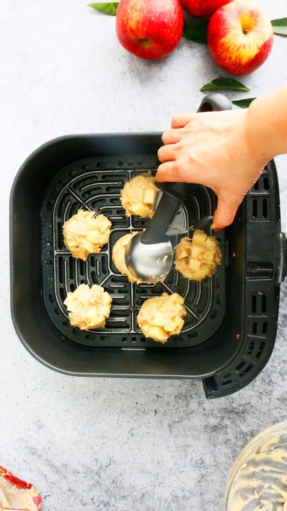 scooping apple fritter batter in an air fryer basket