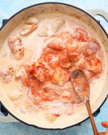 chicken vodka pasta cooking in a white pan.