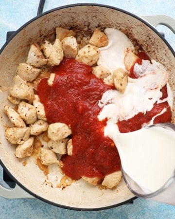 chicken vodka pasta cooking in a white pan.