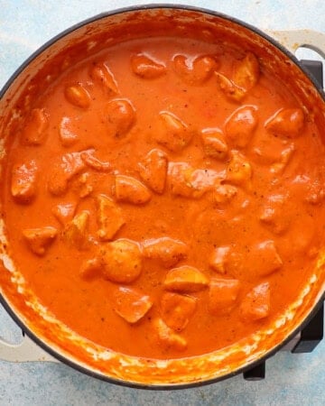 chicken vodka pasta cooking in a white pan.