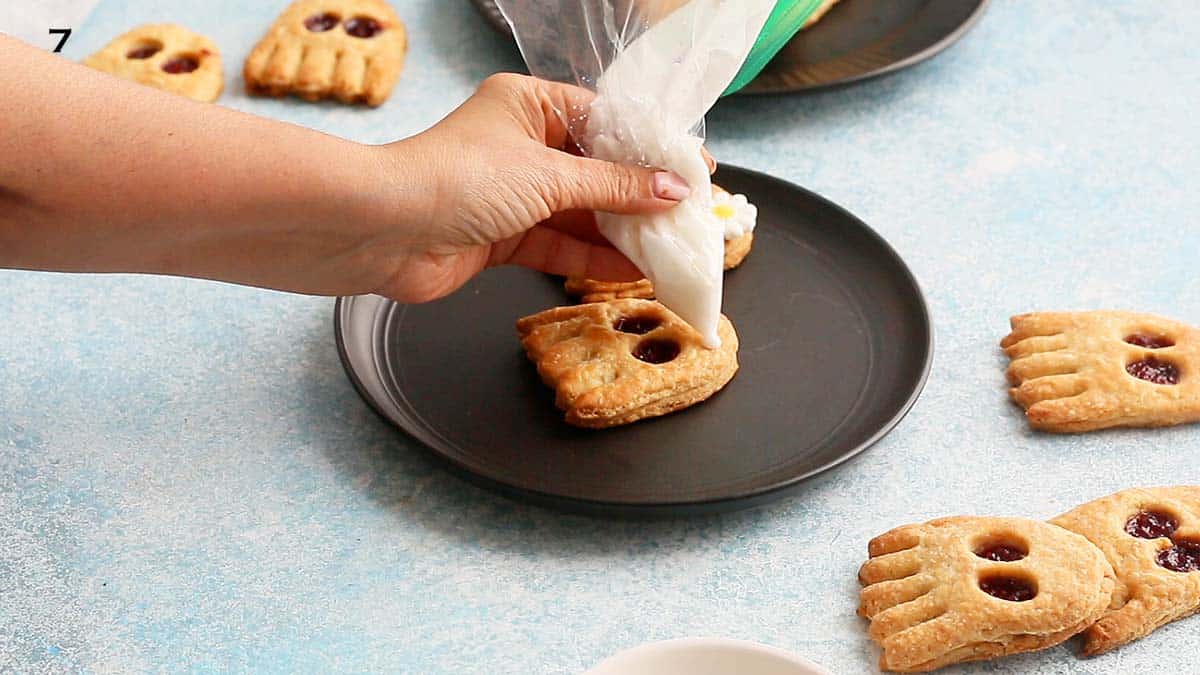 a hand squeezing sugar glaze using a zip lock bag on a ghost pop tart.