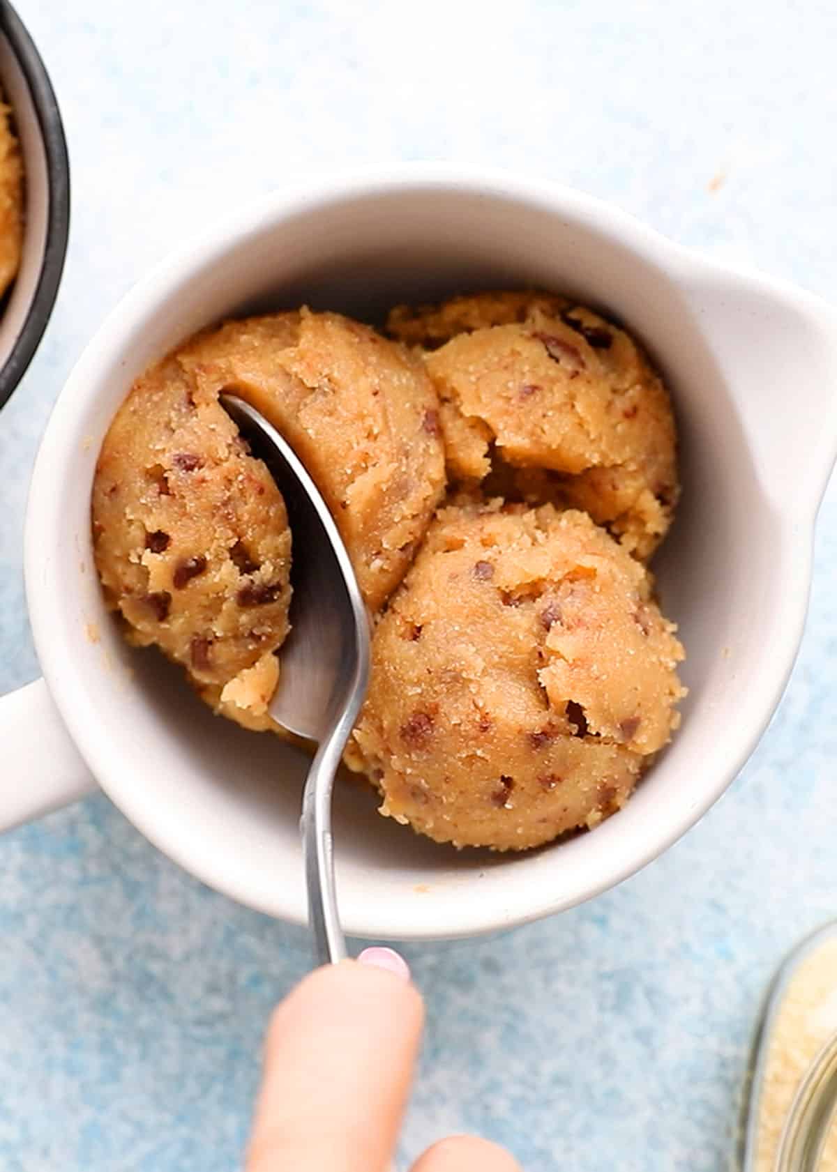 white bowl with scoops of raw cookie dough along with a spoon.