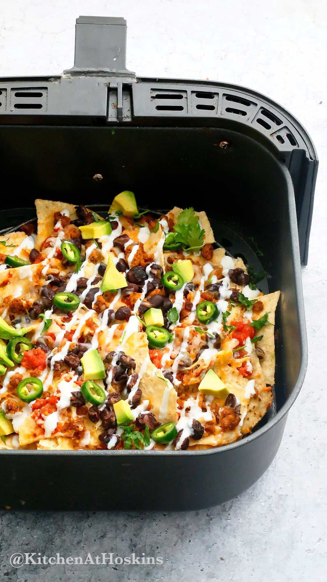 air fryer basket with loaded cheesy nachos