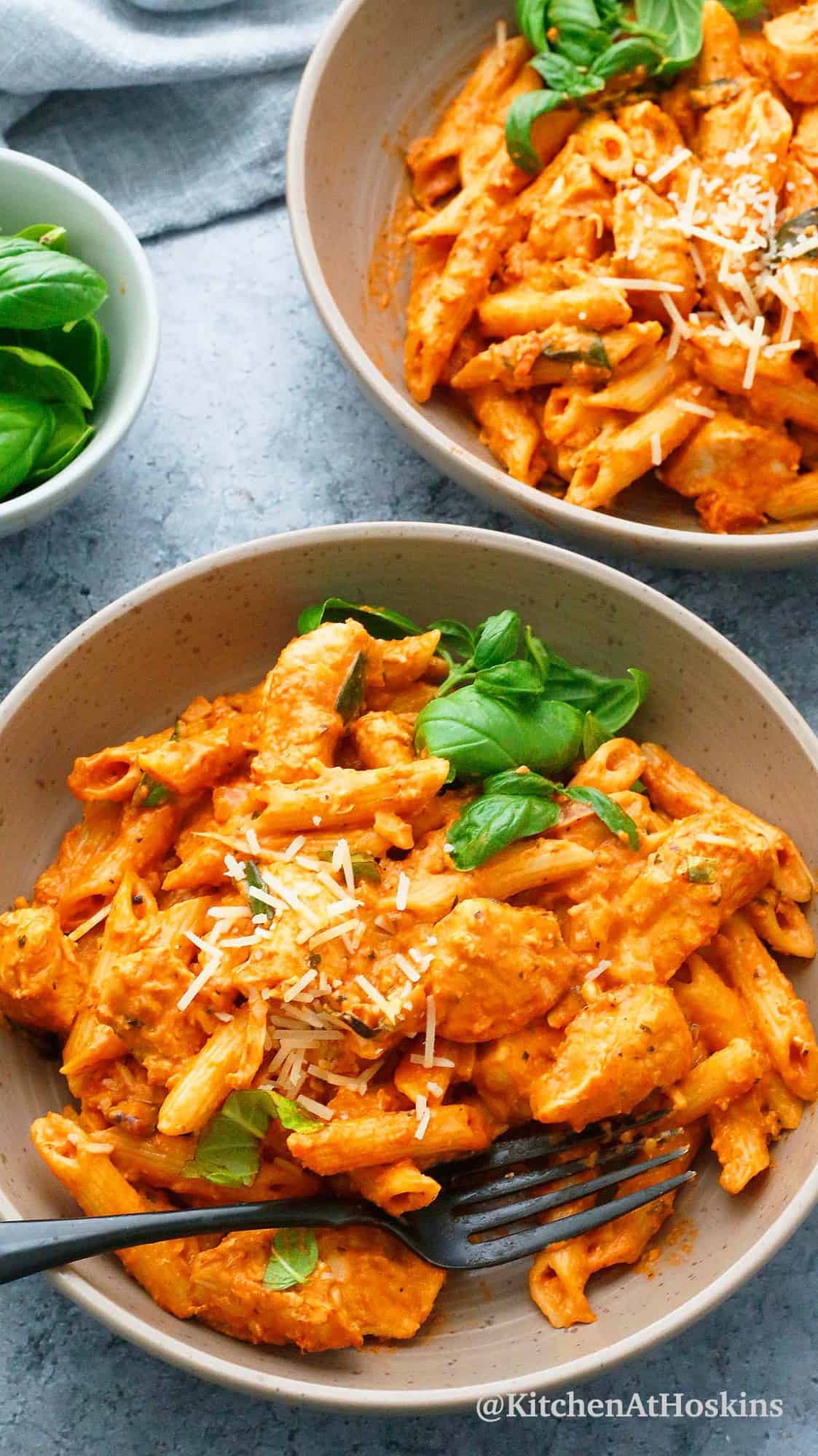 chicken penne all vodka served in bowls and garnished with basil.