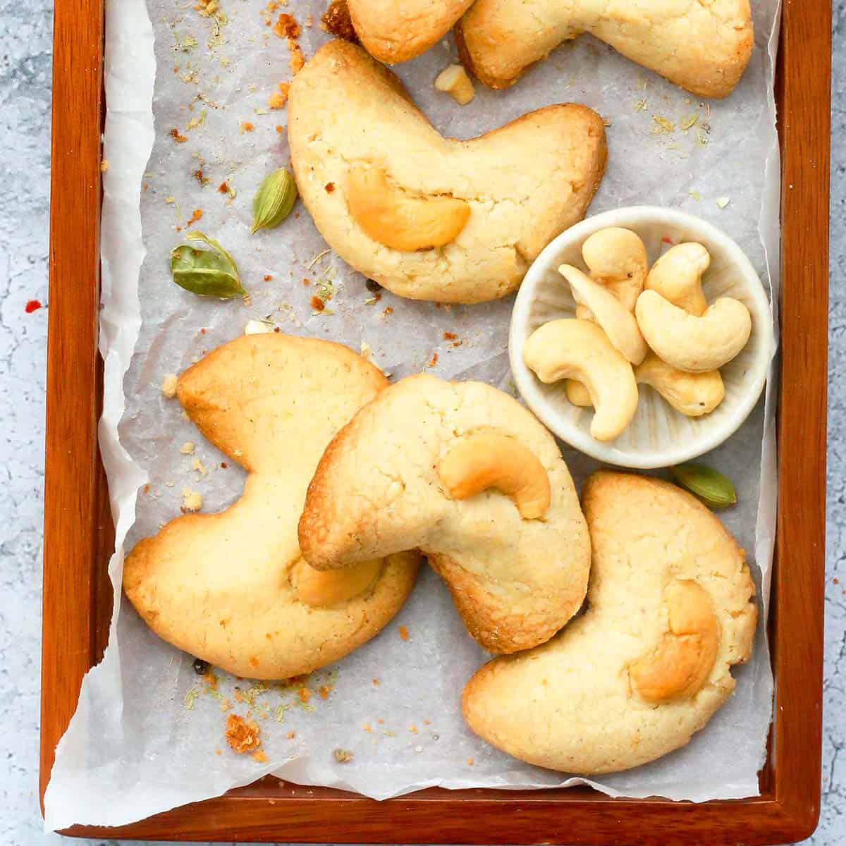 baked cashew cookies on a tray garnished with raw cashews.