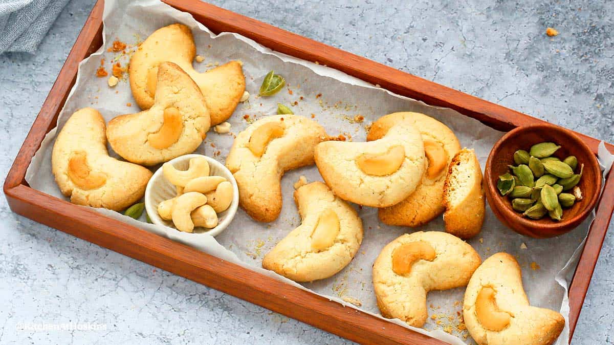 A wooden tray with baked cookies with cashews.