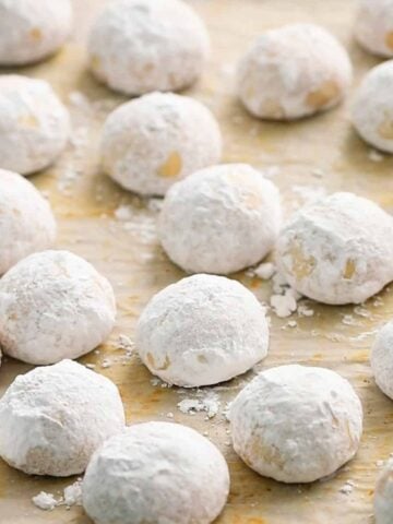 white snowball cookies placed on a parchment lined baking sheet.