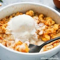 air fryer apple crisp topped with vanilla ice cream along with two spoons