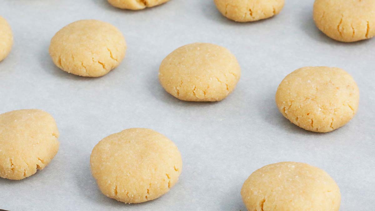 Almond flour cookie dough discs on a baking sheet.