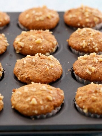 12 mini banana muffins in a metal muffin pan.