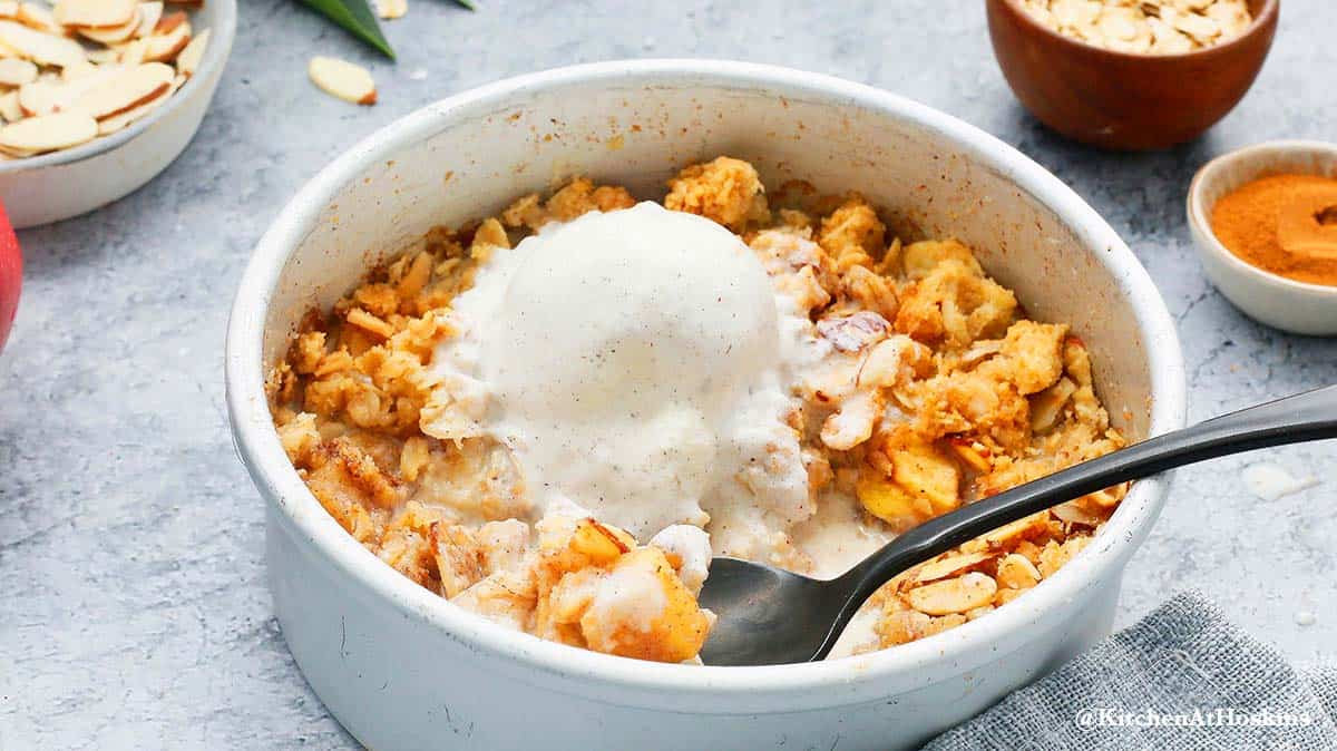 Baking pan with apple crisp made in air fryer topped with vanilla ice cream 