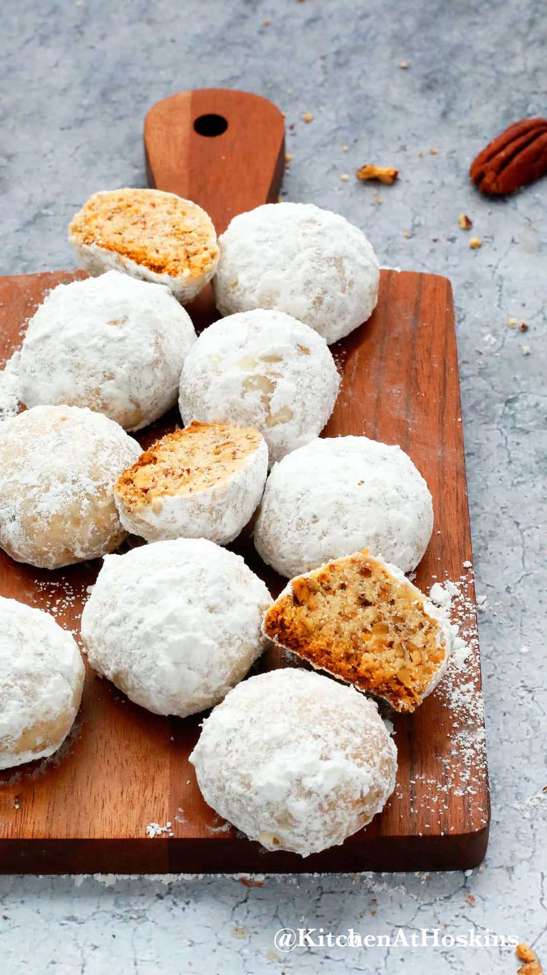 pecan snowball cookies placed on a wooden board.