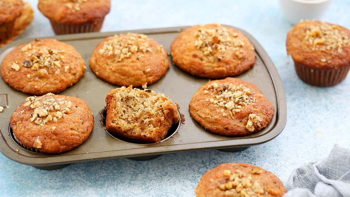 6 baked persimmon muffins in a metal muffin pan.